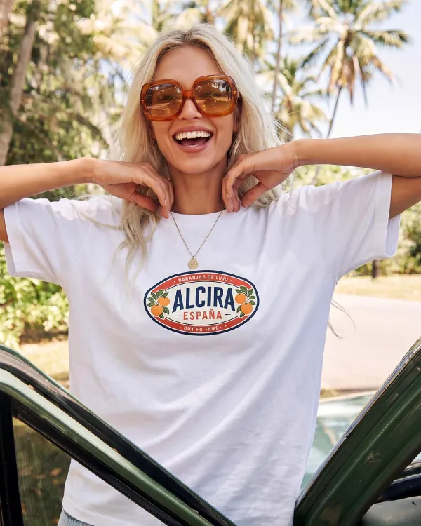 Девушка в белой футболке AlCira España Out Fo Fame с принтом спереди у автомобиля